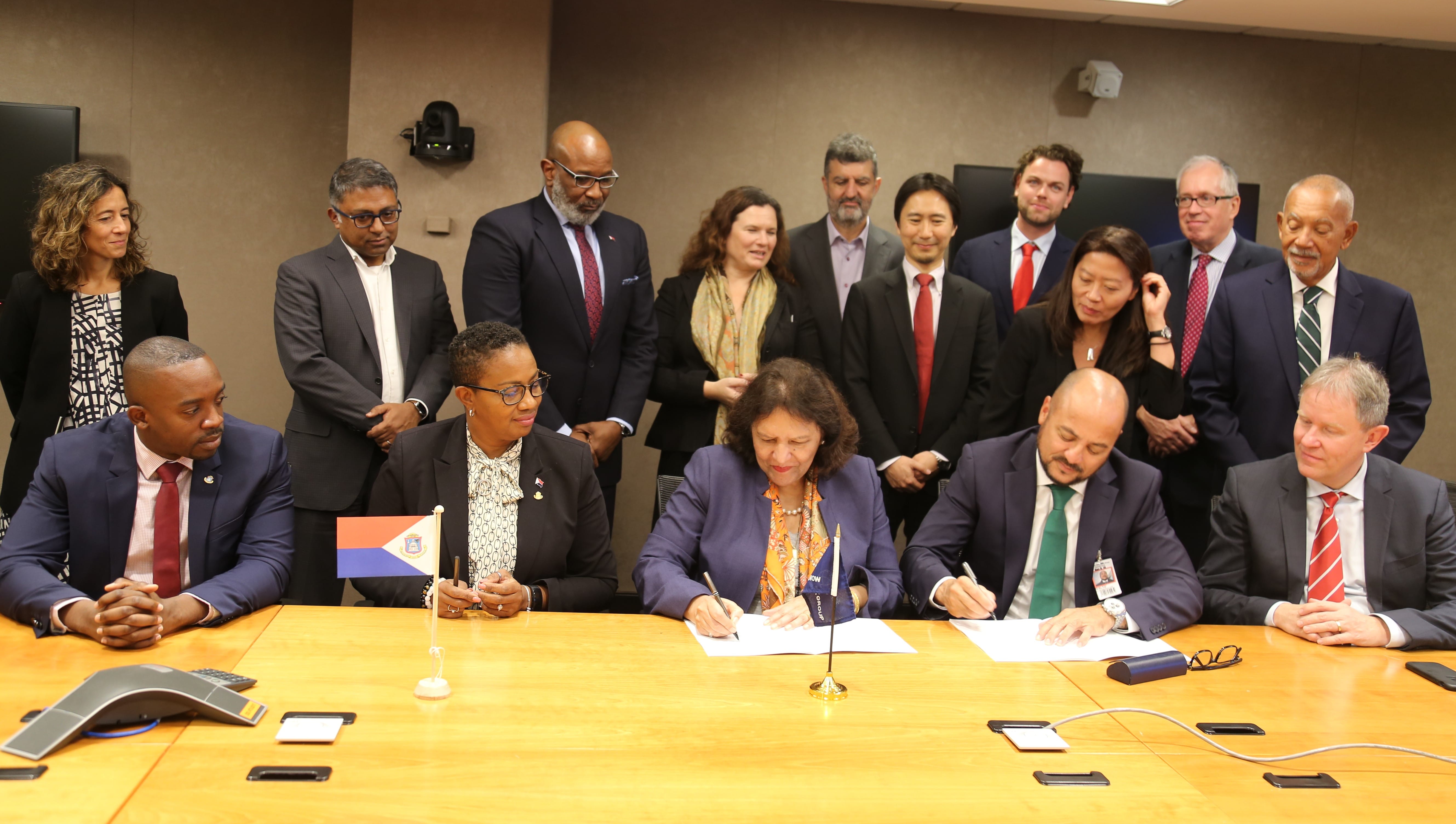 The delegation looks on as the SXM Airport CEO, Brian Mingo (seated left) and the World Bank Country Director, Tahseen Sayed (seated right) signs the official agreement.